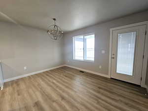 Unfurnished dining area featuring light wood-type flooring and a chandelier