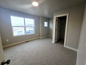 Unfurnished bedroom featuring a closet, a walk in closet, and carpet