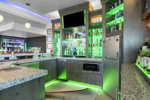 Interior space featuring sink, appliances with stainless steel finishes, pendant lighting, and light stone countertops