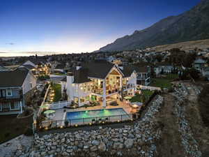 Back house at dusk featuring a fenced in pool, a patio area, and a mountain view