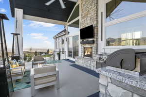 View of patio / terrace with ceiling fan, an outdoor living space with a fireplace, and exterior kitchen