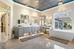 Bathroom with crown molding, a tub to relax in, and vanity