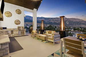 Patio terrace at dusk featuring an outdoor living space with a fire pit, a mountain view, area for grilling, and exterior kitchen