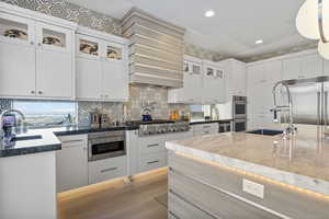 Kitchen featuring decorative light fixtures, sink, white cabinets, and built in appliances