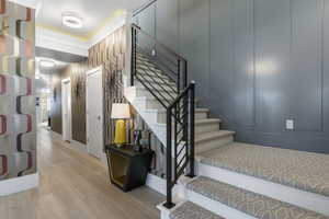 Stairway with wood-type flooring and crown molding