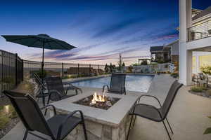 Pool at dusk with a patio area and a fire pit