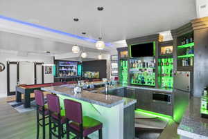 Kitchen with decorative light fixtures, stainless steel fridge, light hardwood / wood-style flooring, and dark stone countertops