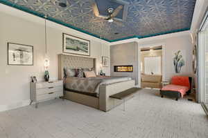 Bedroom with light carpet, a tiled fireplace, and crown molding