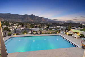 Pool at dusk with a mountain view and a patio area