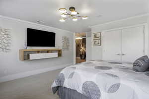 Bedroom with a closet, carpet, ornamental molding, and a notable chandelier