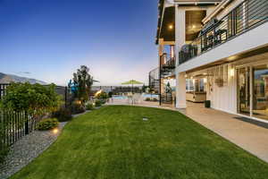 Yard at dusk with a mountain view, a patio, and a fenced in pool