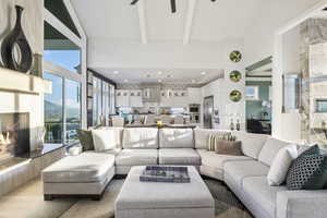 Living room featuring ceiling fan, a fireplace, light hardwood / wood-style floors, beamed ceiling, and a mountain view