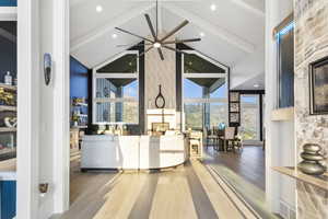 Living room with hardwood / wood-style floors, ceiling fan, a fireplace, high vaulted ceiling, and beamed ceiling