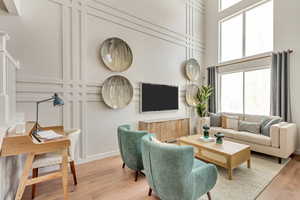 Living room featuring a wealth of natural light, light hardwood / wood-style floors, and a towering ceiling