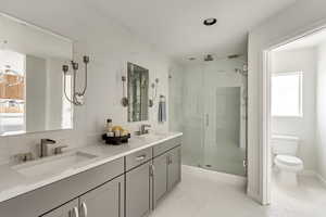 Bathroom with a shower with shower door, toilet, and vanity