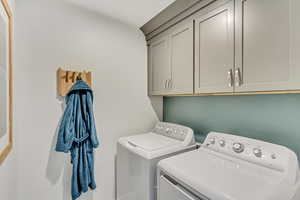 Laundry room featuring washer and clothes dryer and cabinets