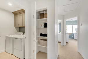 Laundry area featuring cabinets, light carpet, and washing machine and dryer