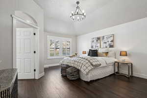 Bedroom featuring lofted ceiling, dark hardwood / wood-style flooring, and a chandelier