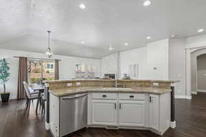 Kitchen featuring sink, white cabinets, dishwasher, a center island with sink, and pendant lighting. Plantaion shutters