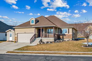 View of front of property with a garage, covered porch, and a front lawn