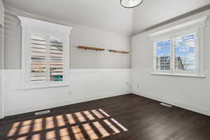 Unfurnished bedroom room featuring vaulted ceiling and dark hardwood / wood-style flooring. Plantation shutters.