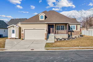 View of front of home featuring central air condition unit, a porch, a garage, a mountain view, and a front yard