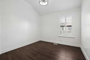 Unfurnished bedroom room with lofted ceiling and dark hardwood / wood-style floors