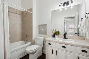 Full bathroom featuring shower / bathtub combination with curtain, vanity, and toilet