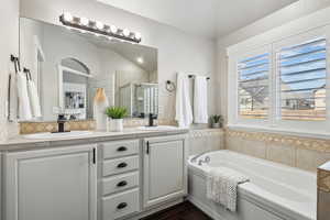 Bathroom featuring lofted ceiling, wood-type flooring, decorative backsplash, vanity, and plus walk in shower