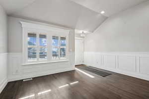 Living room with an inviting chandelier, vaulted ceiling, and dark hardwood / wood-style floors. Plantation shutters.