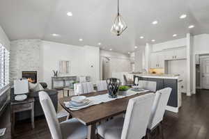 Dining space featuring lofted ceiling, sink, dark hardwood / wood-style floors, and a stone fireplace