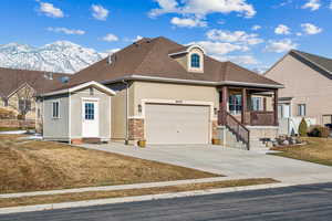 View of front of house featuring a front yard, a garage, covered porch, and a mountain view