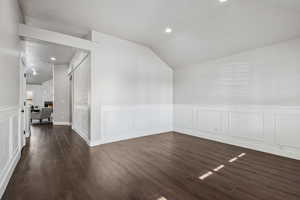 Living room with lofted ceiling, a fireplace, and dark wood-type flooring