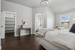 Bedroom featuring a spacious closet, a closet, dark hardwood / wood-style floors, ensuite bath, and a chandelier