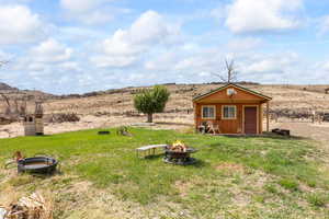 View of yard with a fire pit, an outbuilding, and a rural view