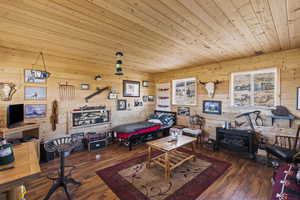 Rec room featuring a wood stove, wood ceiling, wood walls, and hardwood / wood-style floors