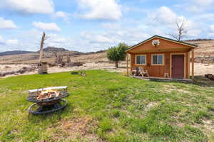 View of grassy yard with a fire pit, an outbuilding, and a mountain view