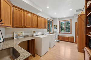 Clothes washing area with cabinets, light hardwood / wood-style flooring, sink, and washing machine and dryer