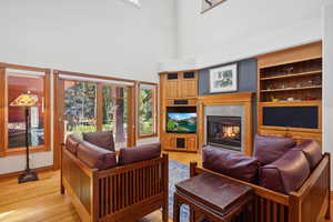 Living room featuring a multi sided fireplace, light hardwood / wood-style floors, and a wealth of natural light