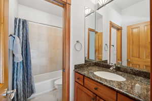 Full bathroom with toilet, tile patterned floors, vanity, and shower / bath combo with shower curtain