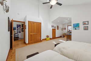 Bedroom featuring ceiling fan, light hardwood / wood-style floors, and high vaulted ceiling