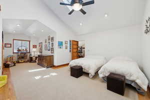 Bedroom with ceiling fan, light carpet, and lofted ceiling