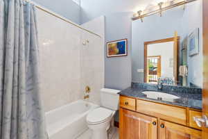 Full bathroom featuring toilet, vanity, and shower / bath combination with curtain