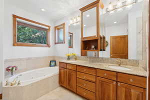 Bathroom featuring tiled tub and vanity