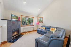 Living room featuring hardwood / wood-style floors, a tile fireplace, and lofted ceiling