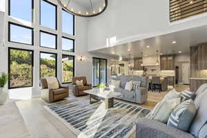 Living room with a notable chandelier, a towering ceiling, and light hardwood / wood-style flooring