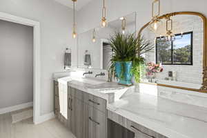 Bathroom featuring tiled tub, vanity, and a chandelier