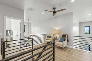 Interior space with ceiling fan with notable chandelier and light hardwood / wood-style floors