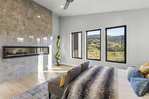 Bedroom with light wood-type flooring, ceiling fan, lofted ceiling, and a tile fireplace