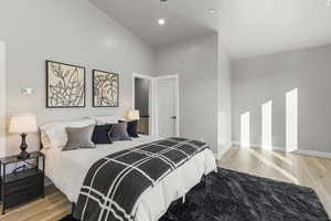 Bedroom with light wood-type flooring and high vaulted ceiling